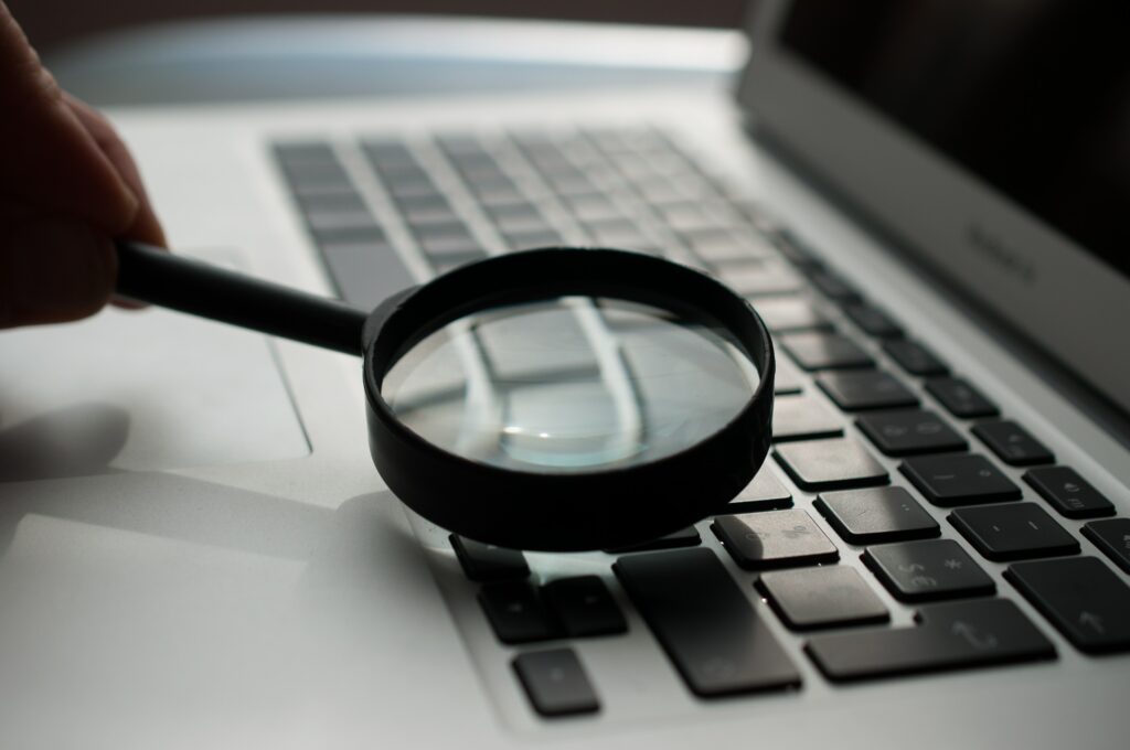 Image of a magnifying glass, next to a laptop